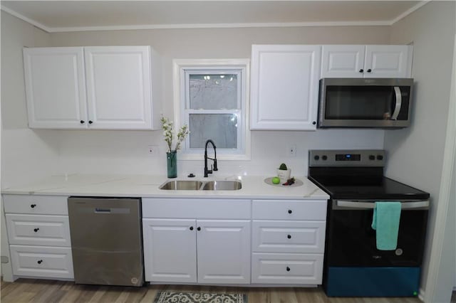 kitchen with sink, white cabinetry, appliances with stainless steel finishes, hardwood / wood-style flooring, and light stone countertops