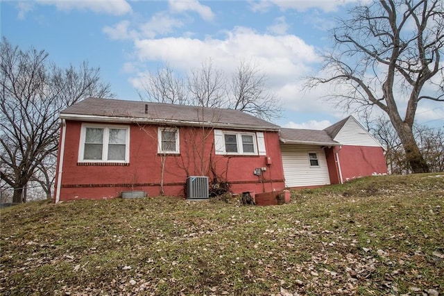 rear view of property featuring cooling unit and a lawn