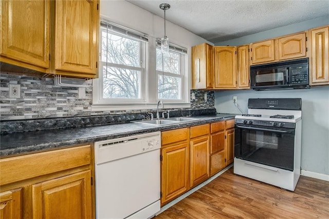 kitchen with pendant lighting, sink, light wood-type flooring, decorative backsplash, and white appliances