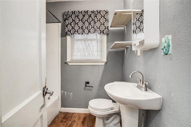 bathroom featuring hardwood / wood-style flooring, toilet, and bathtub / shower combination