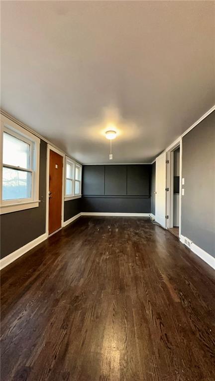 unfurnished living room with dark wood-style floors and baseboards