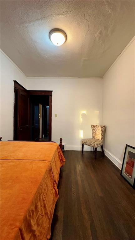 unfurnished bedroom featuring dark wood-style flooring, a textured ceiling, and baseboards