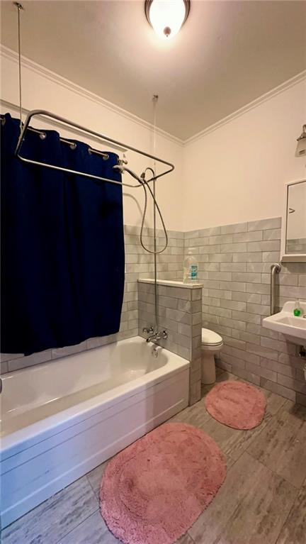 full bathroom with crown molding, tile walls, toilet, and bathing tub / shower combination