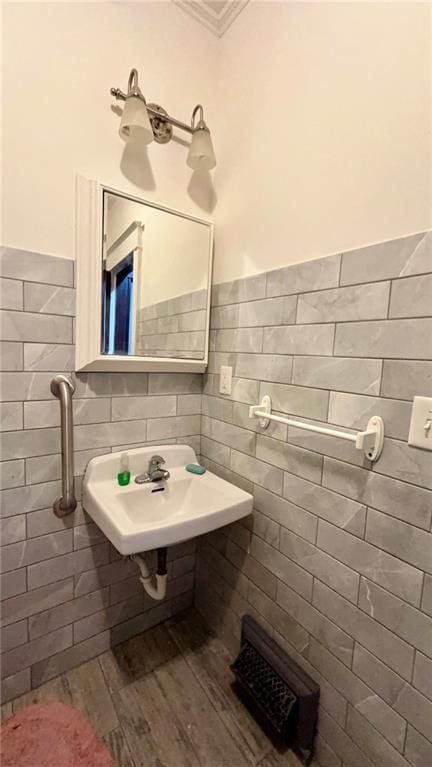 bathroom with a wainscoted wall, crown molding, tile walls, and a sink