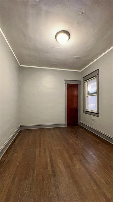 unfurnished room featuring dark wood-style floors, baseboards, and crown molding