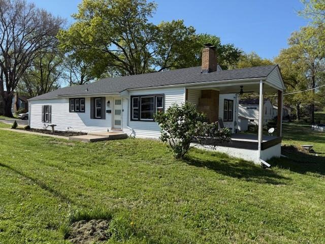 back of property with a chimney, a yard, and an attached carport