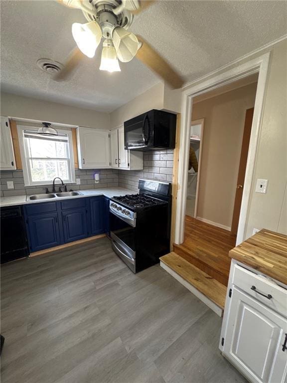 kitchen featuring blue cabinets, sink, black appliances, light wood-type flooring, and white cabinets