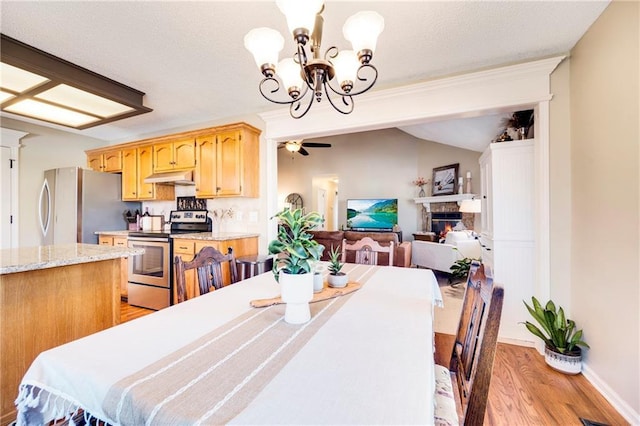 dining space featuring lofted ceiling, ceiling fan with notable chandelier, and light hardwood / wood-style flooring