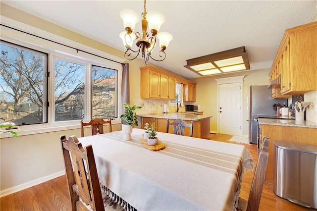 dining space with a chandelier, sink, and light wood-type flooring