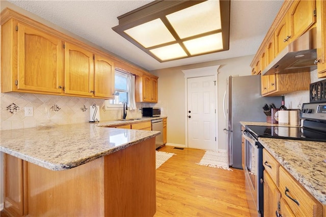 kitchen featuring light stone counters, sink, stainless steel appliances, and kitchen peninsula