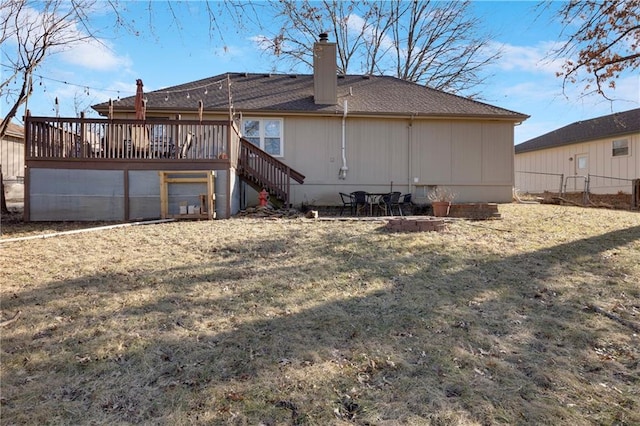 rear view of house with a wooden deck and a lawn