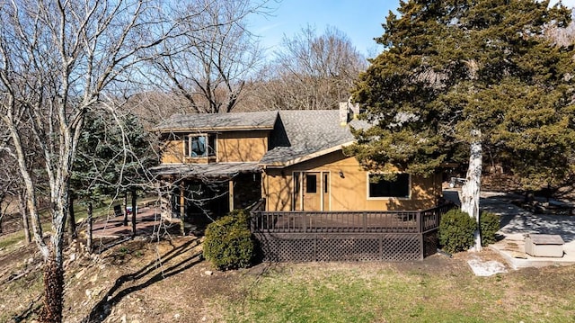 rustic home featuring a deck and a shingled roof