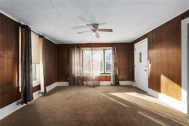 carpeted empty room with ceiling fan and wooden walls