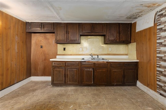 kitchen featuring sink, dark brown cabinets, and wood walls