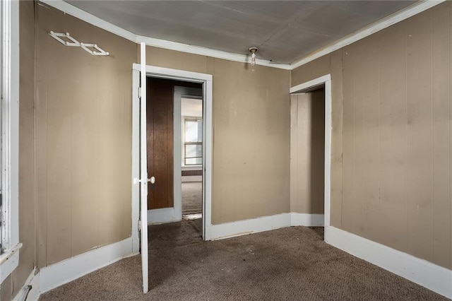 carpeted spare room featuring crown molding and wooden walls