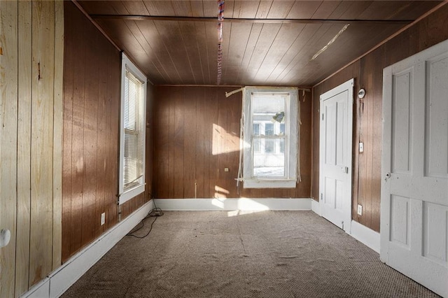 carpeted spare room featuring a baseboard heating unit, wooden walls, and wooden ceiling