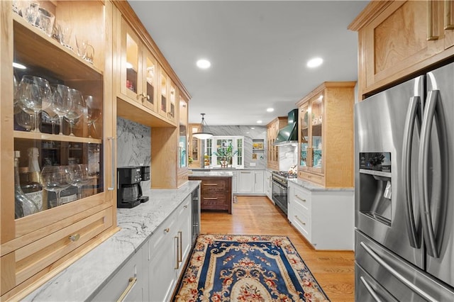 kitchen featuring white cabinetry, light stone countertops, wall chimney exhaust hood, and appliances with stainless steel finishes