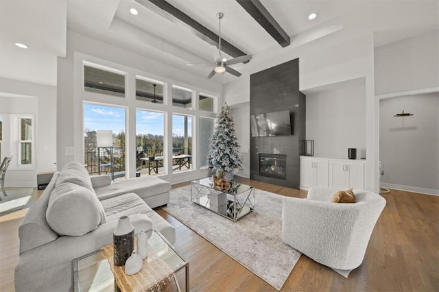 living room with hardwood / wood-style flooring, a fireplace, beamed ceiling, and a towering ceiling