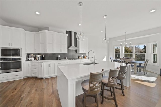 kitchen featuring white cabinets, appliances with stainless steel finishes, sink, and wall chimney range hood