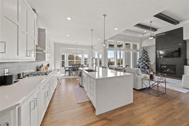 kitchen featuring white cabinetry, sink, an island with sink, and pendant lighting