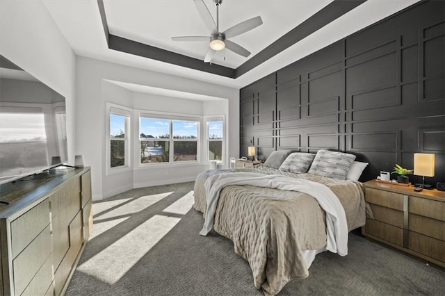 carpeted bedroom featuring ceiling fan and a tray ceiling