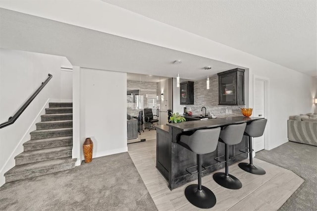 kitchen with hanging light fixtures, light carpet, a kitchen bar, and kitchen peninsula