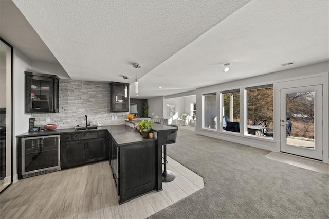 kitchen with sink, hanging light fixtures, a kitchen breakfast bar, tasteful backsplash, and beverage cooler