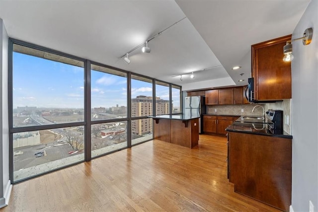 kitchen featuring dark countertops, a city view, freestanding refrigerator, and light wood-style floors