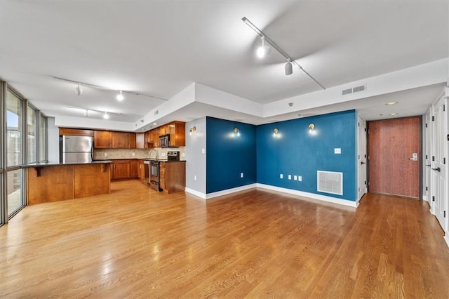 kitchen with open floor plan, visible vents, appliances with stainless steel finishes, and brown cabinets