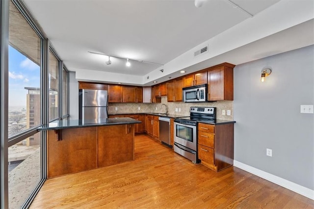 kitchen featuring visible vents, a sink, stainless steel appliances, dark countertops, and backsplash