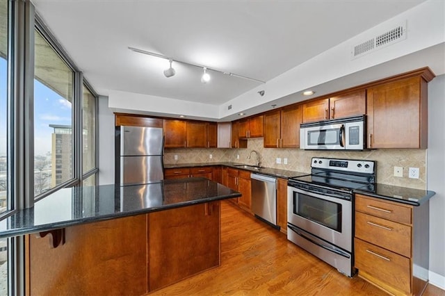 kitchen with light wood finished floors, visible vents, decorative backsplash, stainless steel appliances, and a sink