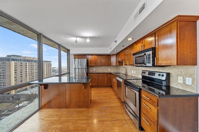 kitchen featuring visible vents, backsplash, appliances with stainless steel finishes, light wood-style floors, and a sink