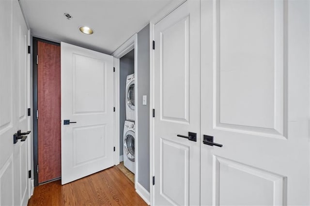 washroom featuring stacked washer and clothes dryer, wood finished floors, and laundry area