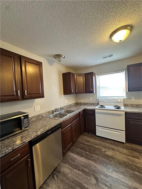 kitchen with sink, dark brown cabinets, stainless steel appliances, and dark hardwood / wood-style floors