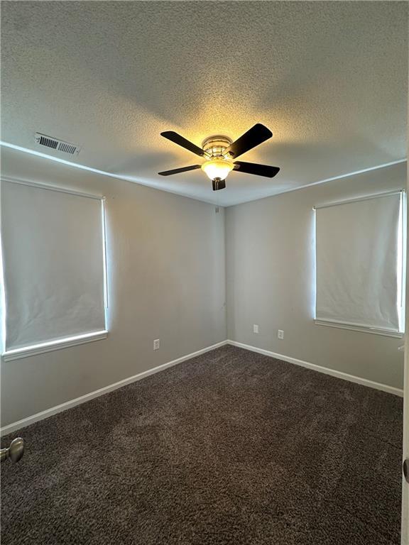 empty room featuring a textured ceiling, carpet floors, and ceiling fan