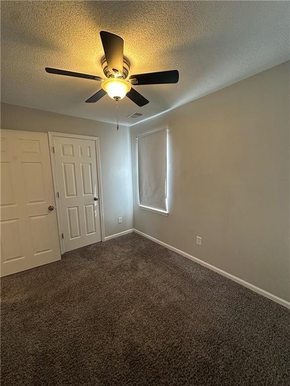 carpeted spare room featuring ceiling fan and a textured ceiling