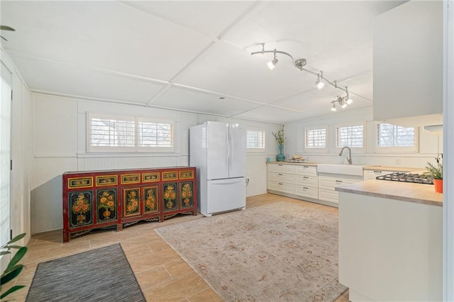 kitchen with white cabinetry, sink, and white fridge