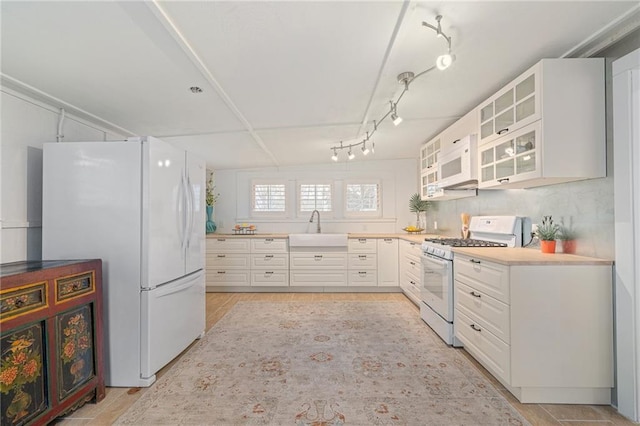 kitchen with white cabinetry, sink, white appliances, and track lighting