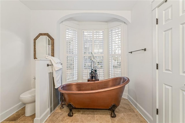 bathroom featuring a washtub, tile patterned floors, and toilet