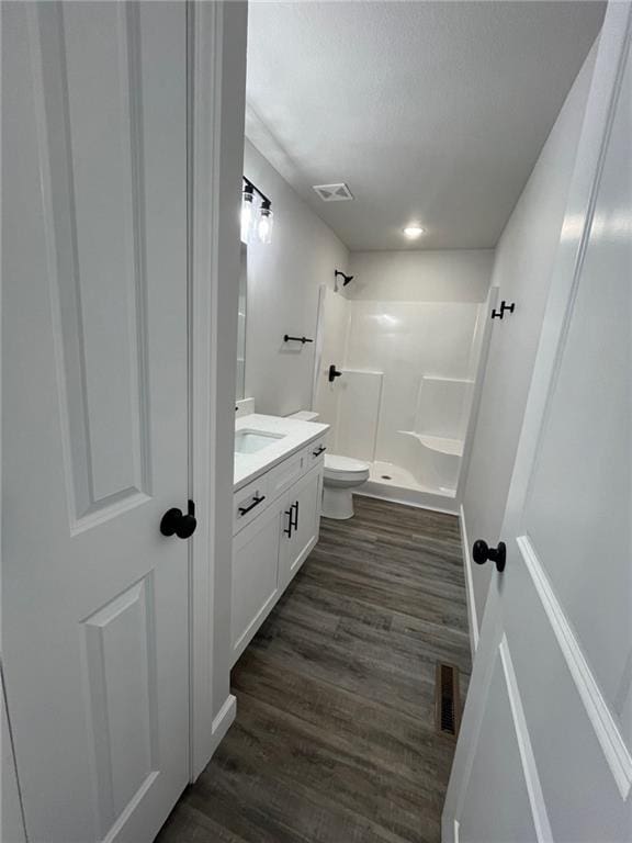 bathroom with wood-type flooring, toilet, vanity, and walk in shower