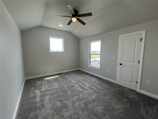 bonus room featuring lofted ceiling, baseboards, dark colored carpet, and a ceiling fan