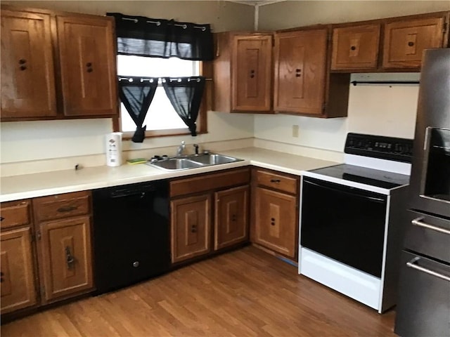 kitchen with sink, electric range, black dishwasher, light hardwood / wood-style floors, and exhaust hood