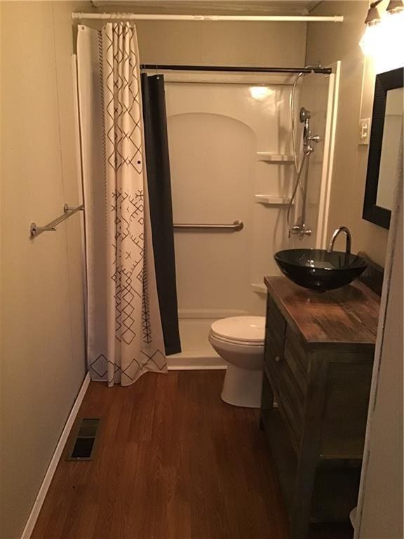 bathroom with hardwood / wood-style flooring, vanity, toilet, and walk in shower