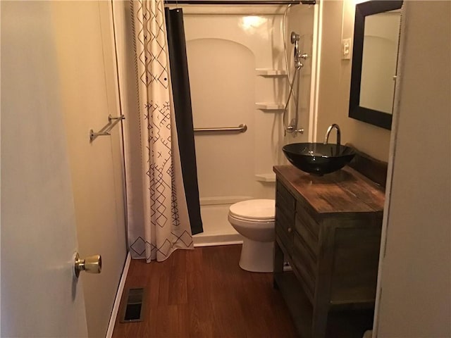 bathroom with wood-type flooring, curtained shower, vanity, and toilet