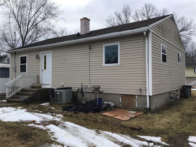 snow covered house featuring central AC unit