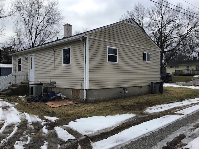 snow covered property with central AC unit