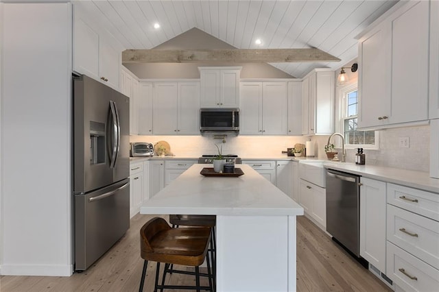 kitchen with appliances with stainless steel finishes, a kitchen island, a kitchen breakfast bar, and white cabinetry