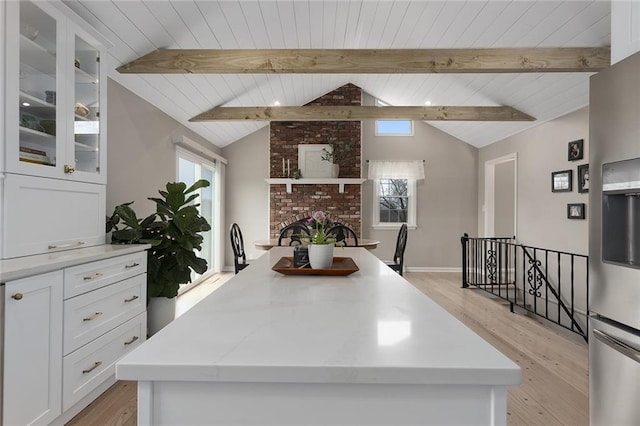 kitchen featuring white cabinets, a center island, a wealth of natural light, and lofted ceiling with beams