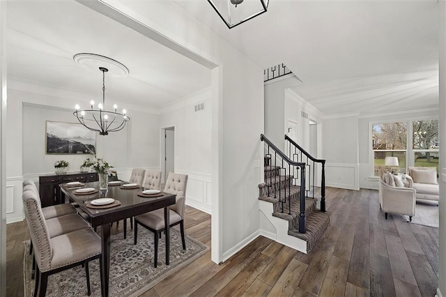 dining area with dark wood-type flooring, ornamental molding, and a notable chandelier