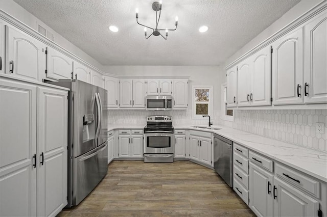 kitchen featuring sink, white cabinetry, light wood-type flooring, appliances with stainless steel finishes, and backsplash